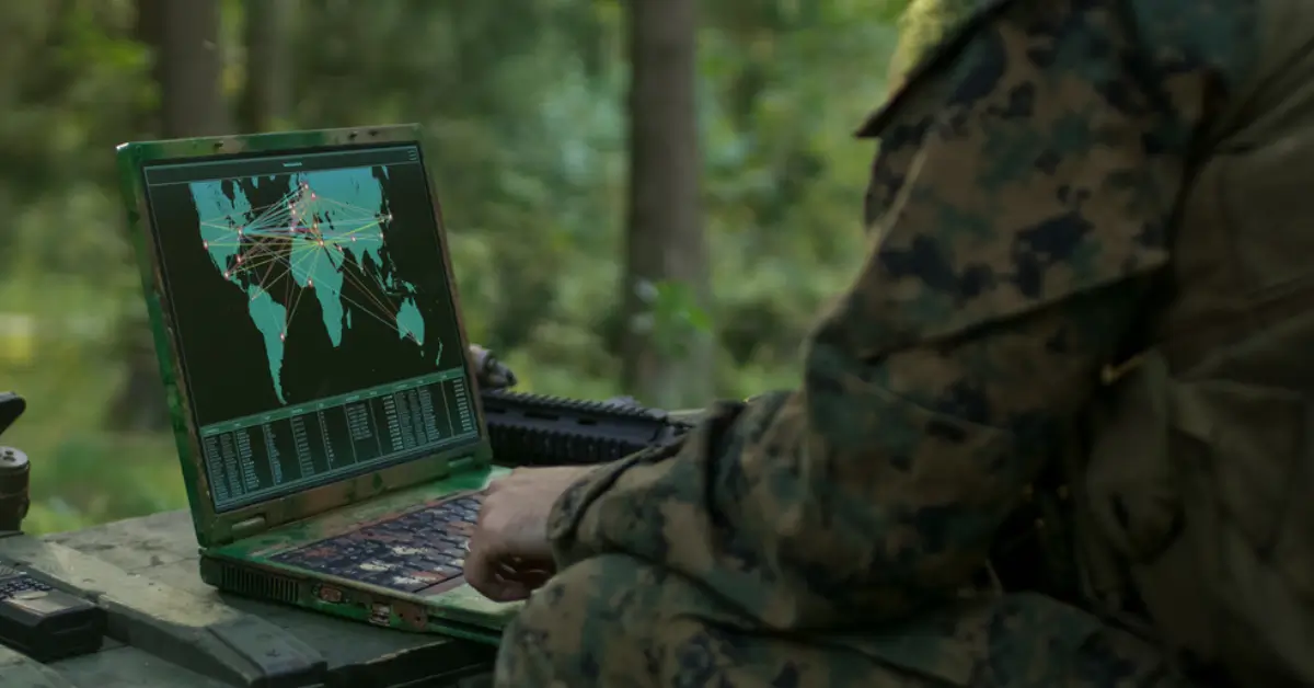 Military Operation in Action, Soldiers Using Military Grade Laptop Use Military Industrial Complex Hardware for Accomplishing International Mission. In the Background Camouflaged Tent on the Forest.